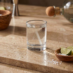 Clear glass with water on a stone surface with limes and salt in the background
