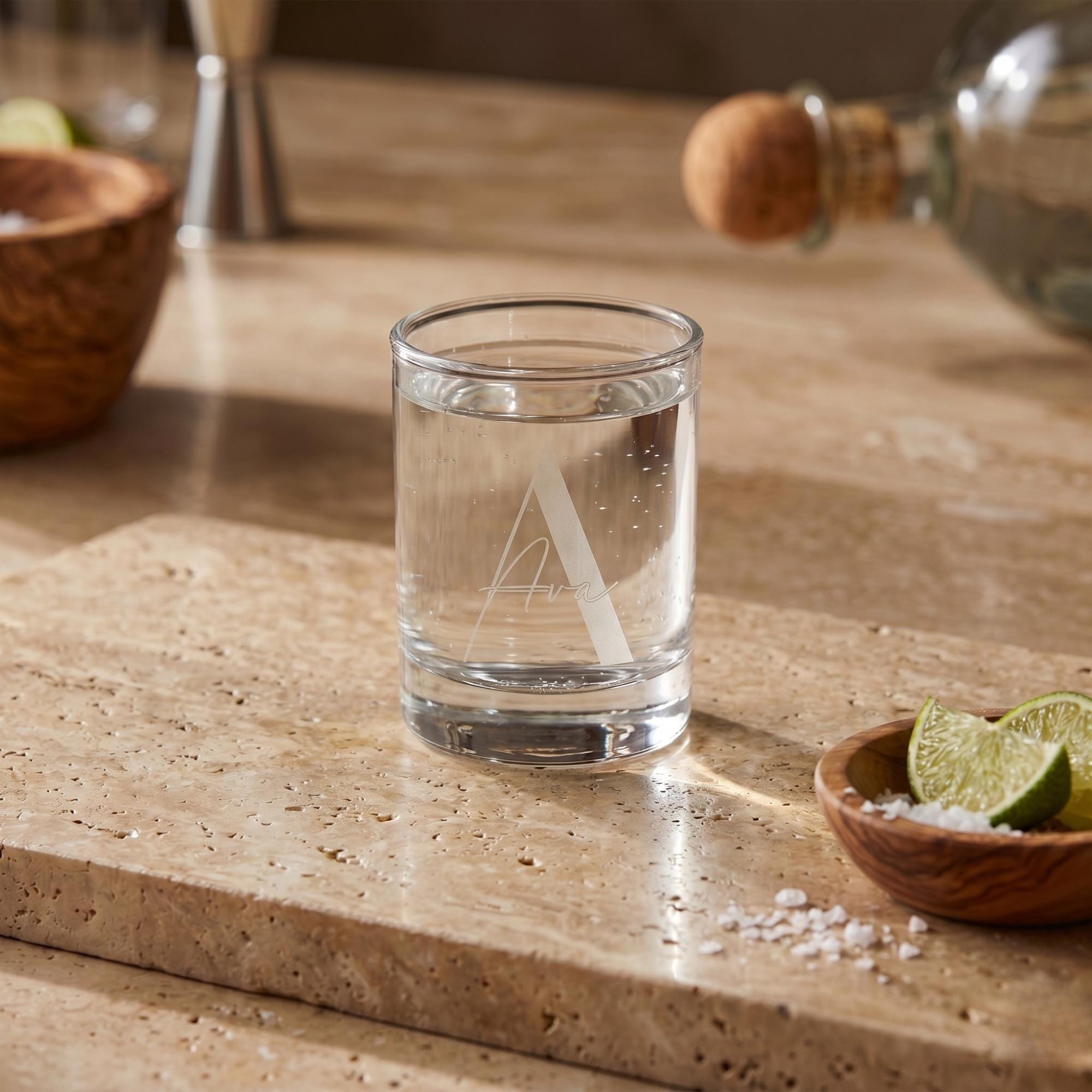 Clear glass with water on a stone surface with limes and salt in the background