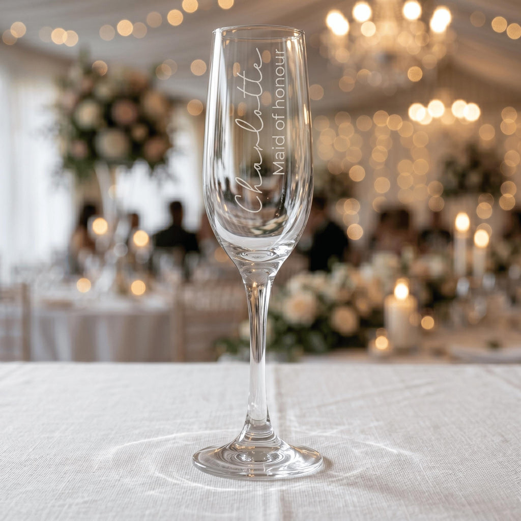 Custom engraved champagne glass for a Maid of Honour named Charlotte, featuring vertical script text on a crystal-clear flute at a luxury wedding reception.