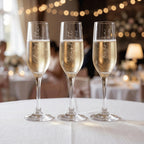 Three champagne glasses with personalised inscriptions on a table with blurred background