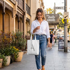 Lifestyle shot showing a woman on Crown Street with a white personalised tote bag. This custom shopping bag is detailed with a large silver letter 'A' and a name, perfect as a unique personalised gift for an eco-conscious Australian lifestyle.