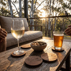 Glass of white wine and a glass of beer on a wooden table with sunset in the background