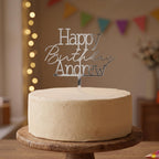 Custom Happy Birthday Andrew silver mirror acrylic cake topper placed on an iced cake.
