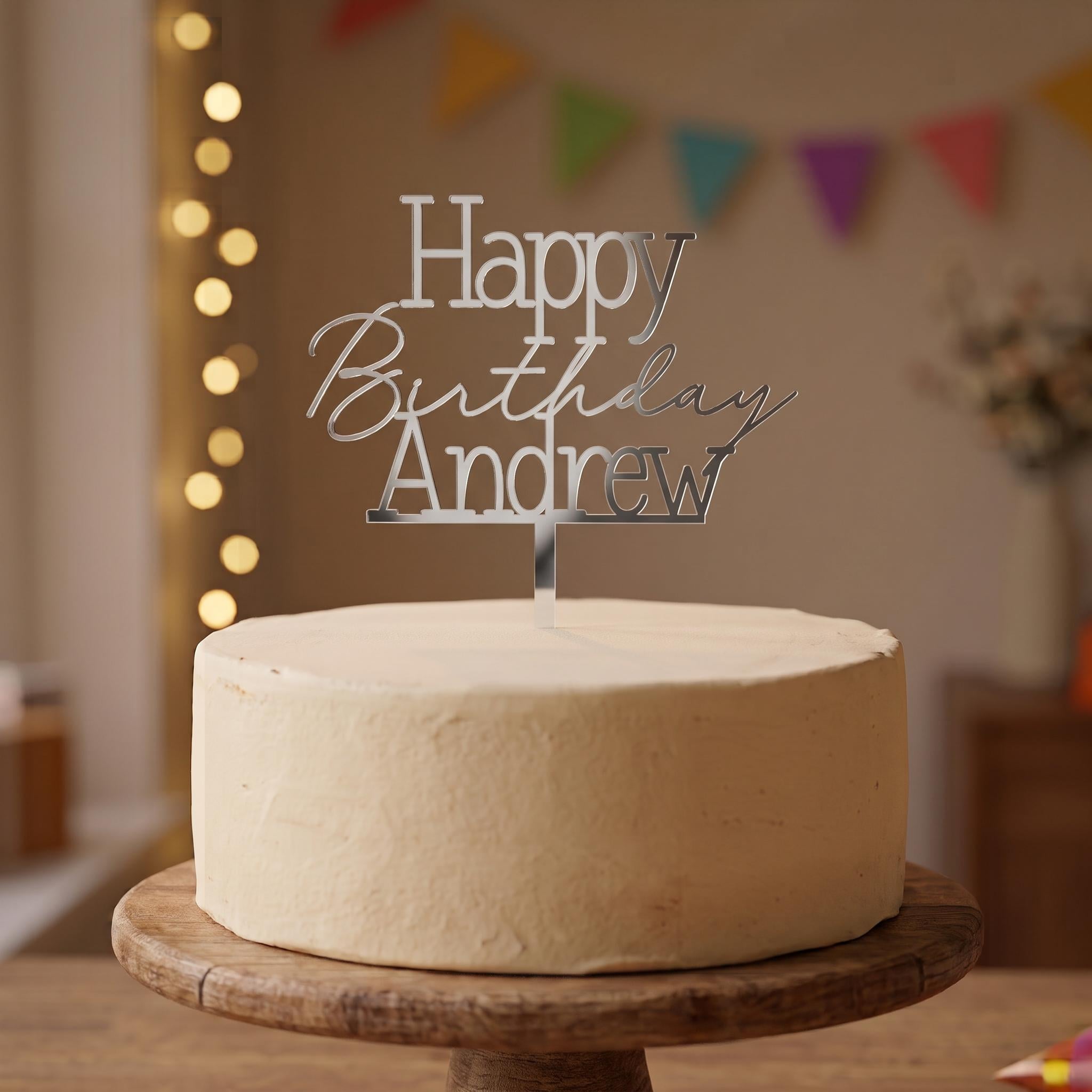 Custom Happy Birthday Andrew silver mirror acrylic cake topper placed on an iced cake.