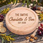 Detail of round engraved cheese cutting platter with custom text reading The Smiths Charlotte and Ben EST 2026 on weathered timber.