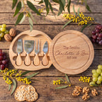 Custom engraved round rubberwood cheese board swiveled open on a rustic timber table showing four cheese knives inside, styled with Australian wattle and eucalyptus.