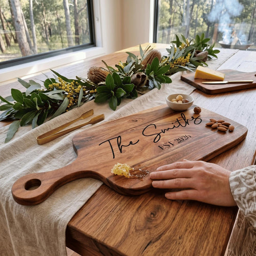 Custom laser engraved acacia timber cheese platter reading The Smiths EST 2026 in script font styled with wattle and honeycomb.