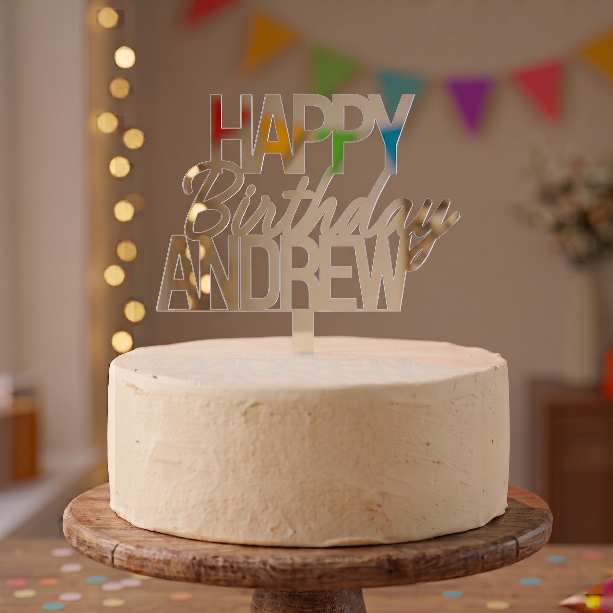 Custom Happy Birthday Andrew silver mirror acrylic cake topper positioned on a celebration cake.