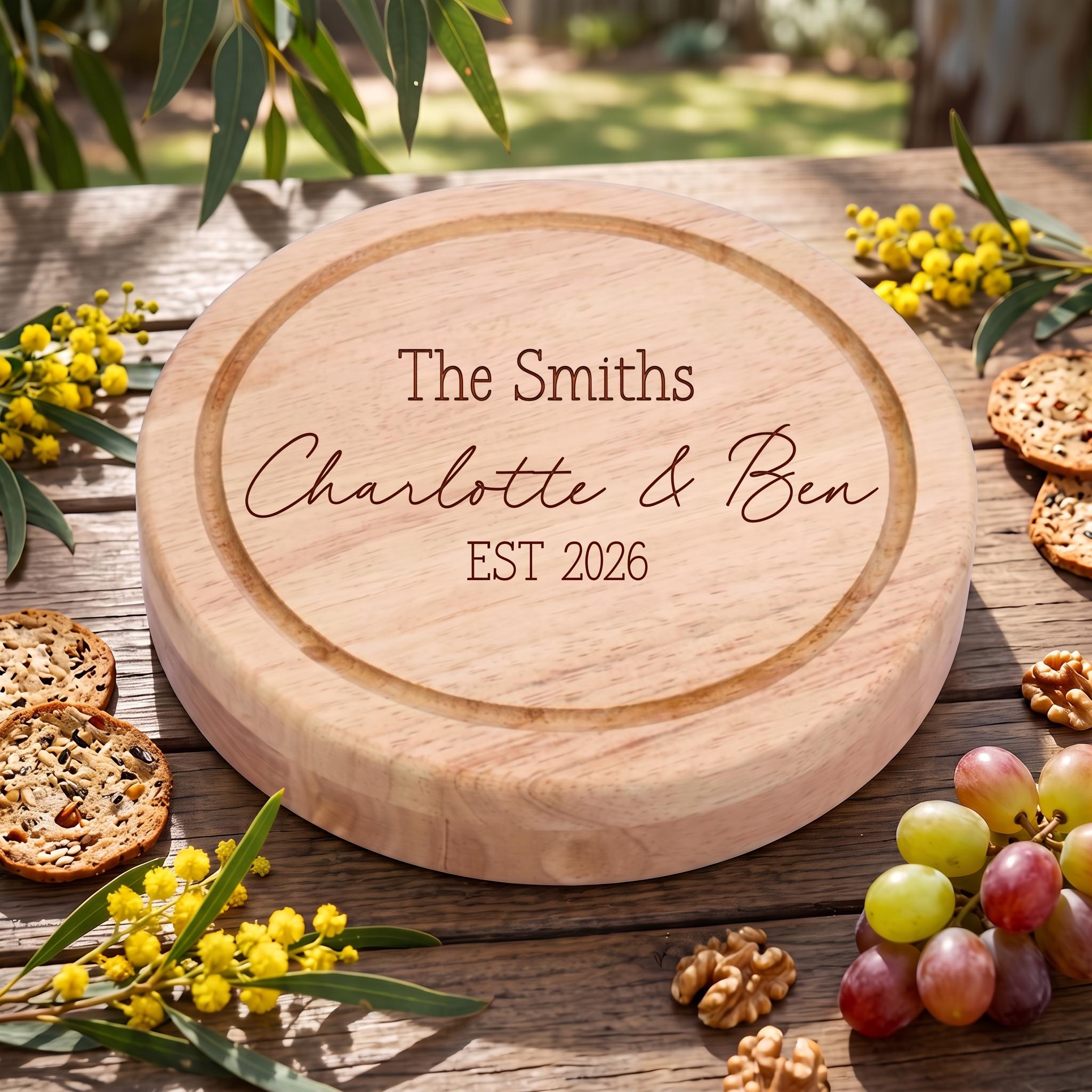 Detail of round engraved timber charcuterie platter with custom text reading The Smiths Charlotte and Ben EST 2026 on weathered wood.