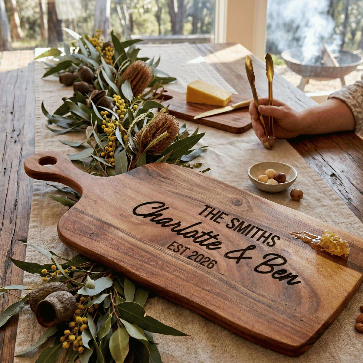 Personalised engraved 40cm by 20cm acacia timber serving board with handle styled on an Australian dining table with charcuterie.