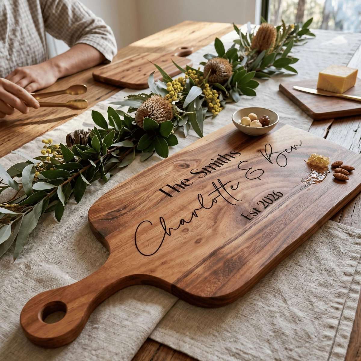 Personalised engraved acacia timber serving board with handle styled on an Australian dining table with charcuterie.