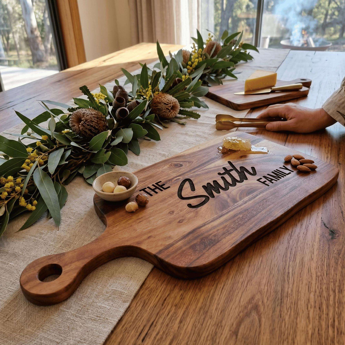 Personalised 40cm by 20cm acacia wood serving board with handle laser engraved in Bold Contemporary typography on natural timber surface.