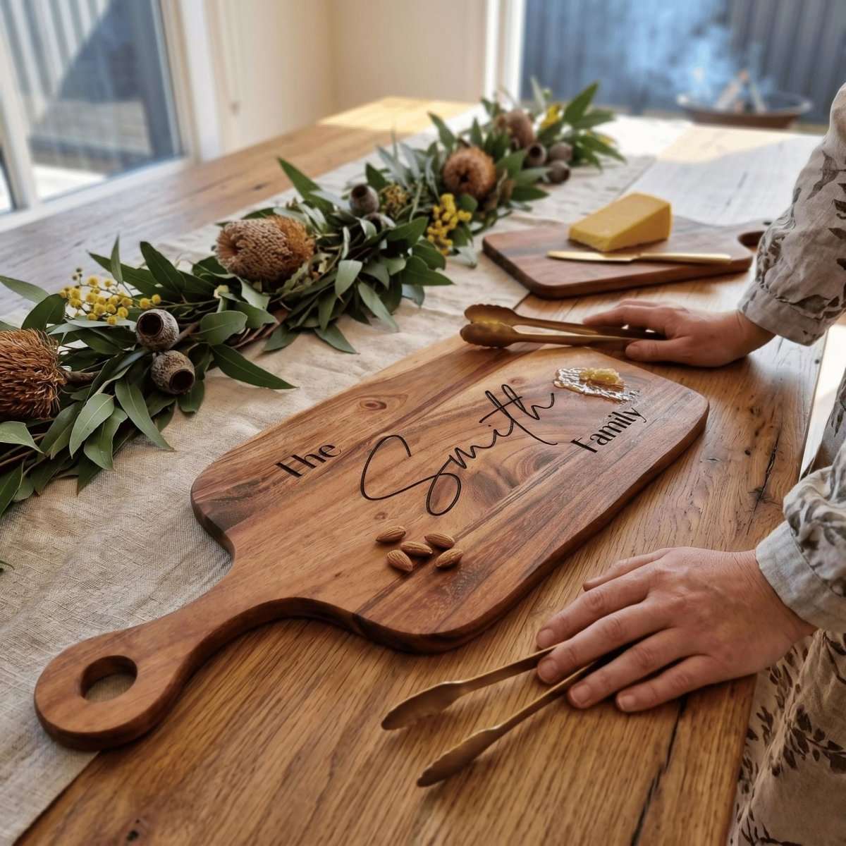 Personalised acacia wood serving board with handle laser engraved in Modern Elegance typography on natural timber surface.