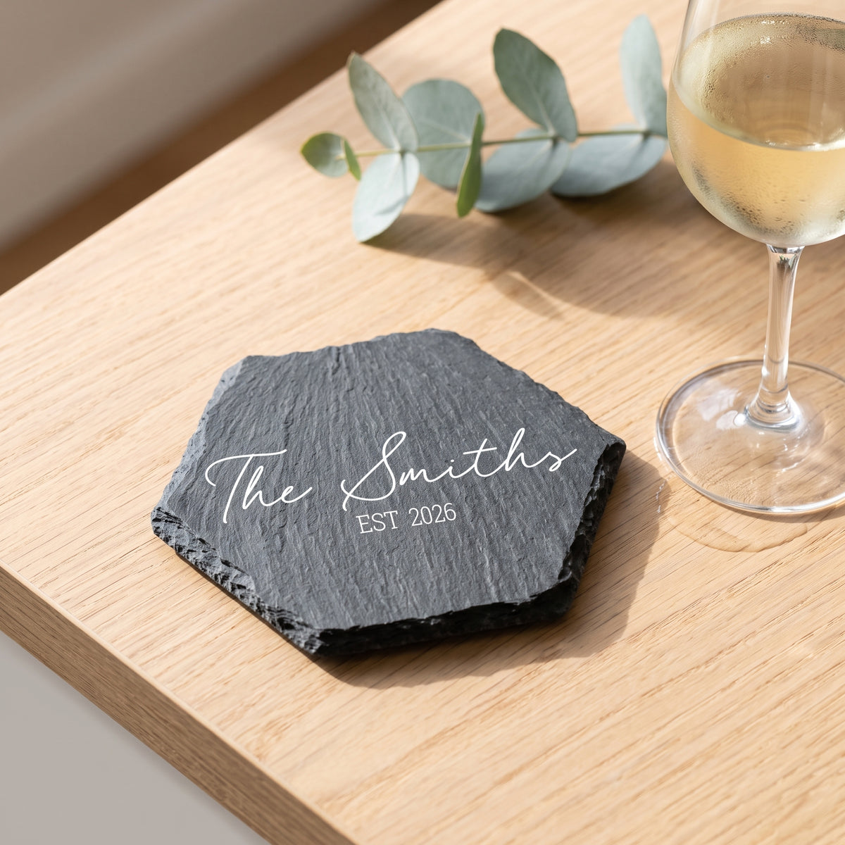 Personalised engraved geometric slate coaster styled with a glass mug on a timber coffee table in Australia.