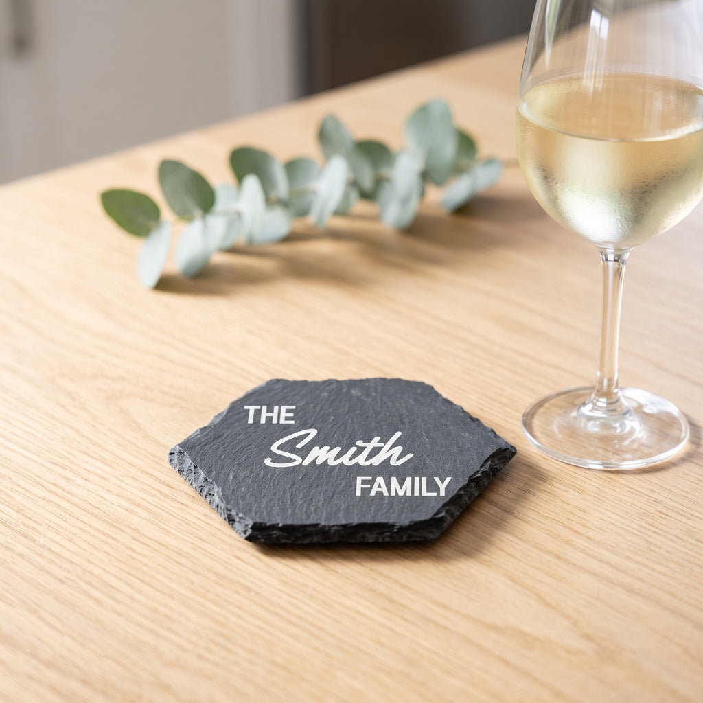 Personalised hexagon slate coaster laser engraved in Bold Contemporary font layout on natural dark grey stone surface.