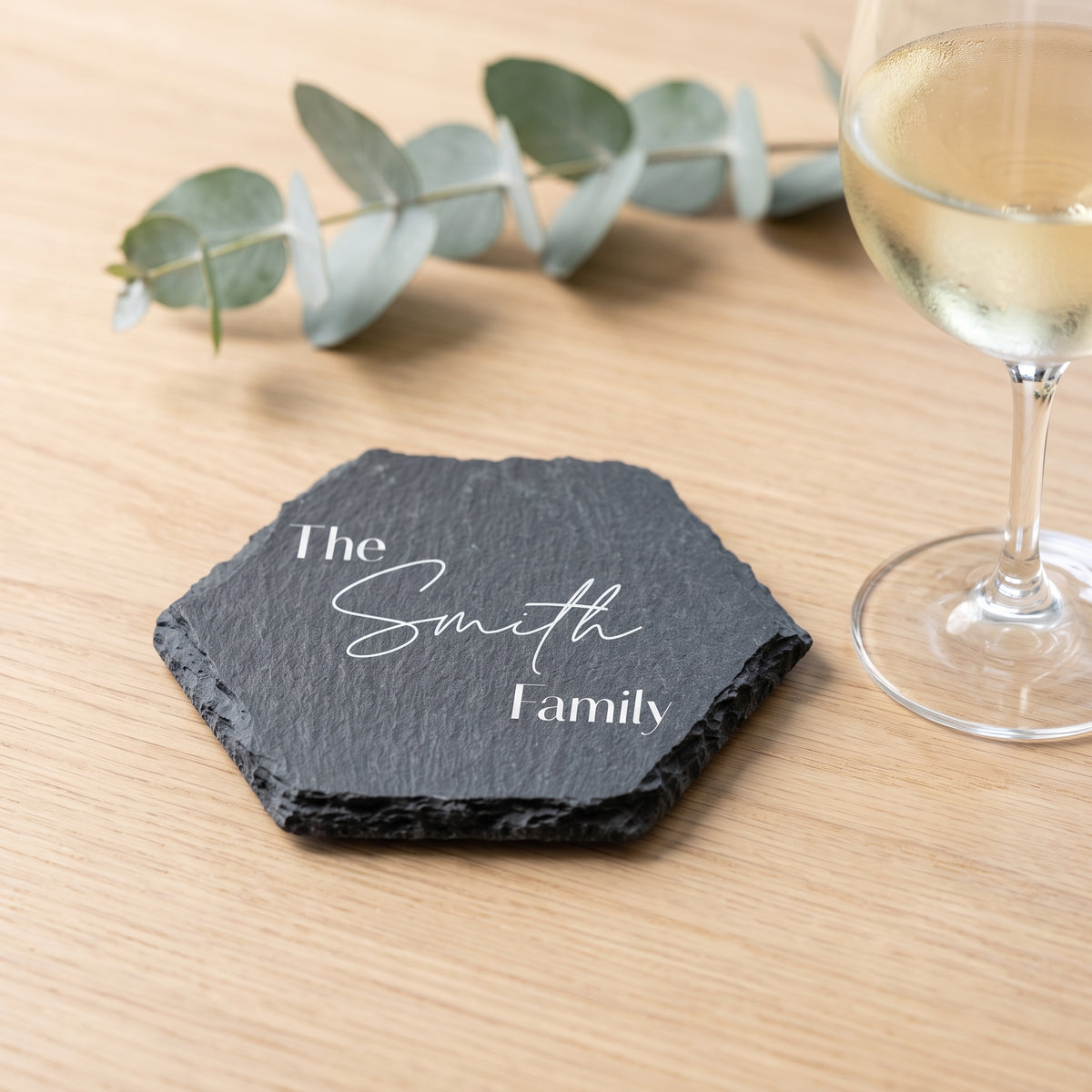 Personalised hexagon slate coaster laser engraved in Modern Elegance font layout on natural dark grey stone surface.