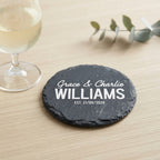 Personalised engraved round slate coaster styled with a drink glass on a timber table in Australia.