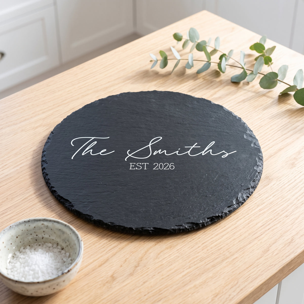 Personalised engraved round slate platter styled with artisanal cheeses and fruit on a wooden table in Australia.