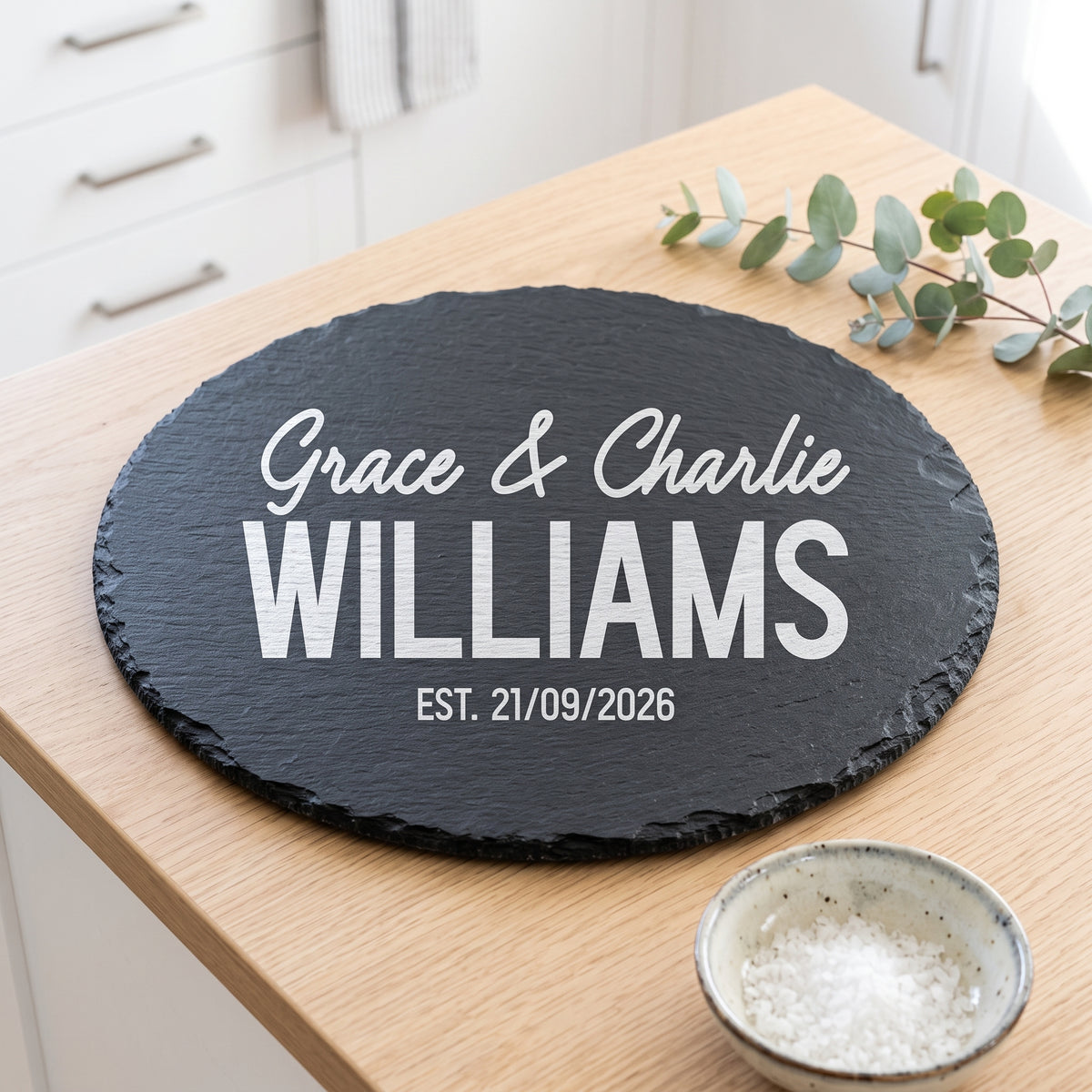 Personalised 30cm round slate platter laser engraved in Bold Contemporary font layout on natural dark grey stone surface.