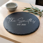 Personalised 30cm round slate platter laser engraved in Modern Elegance font layout on natural dark grey stone surface.