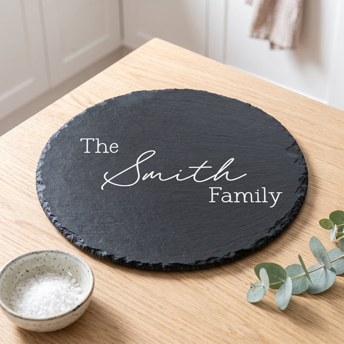 Personalised 30cm round slate platter laser engraved in Timeless Classic font layout on natural dark grey stone surface.