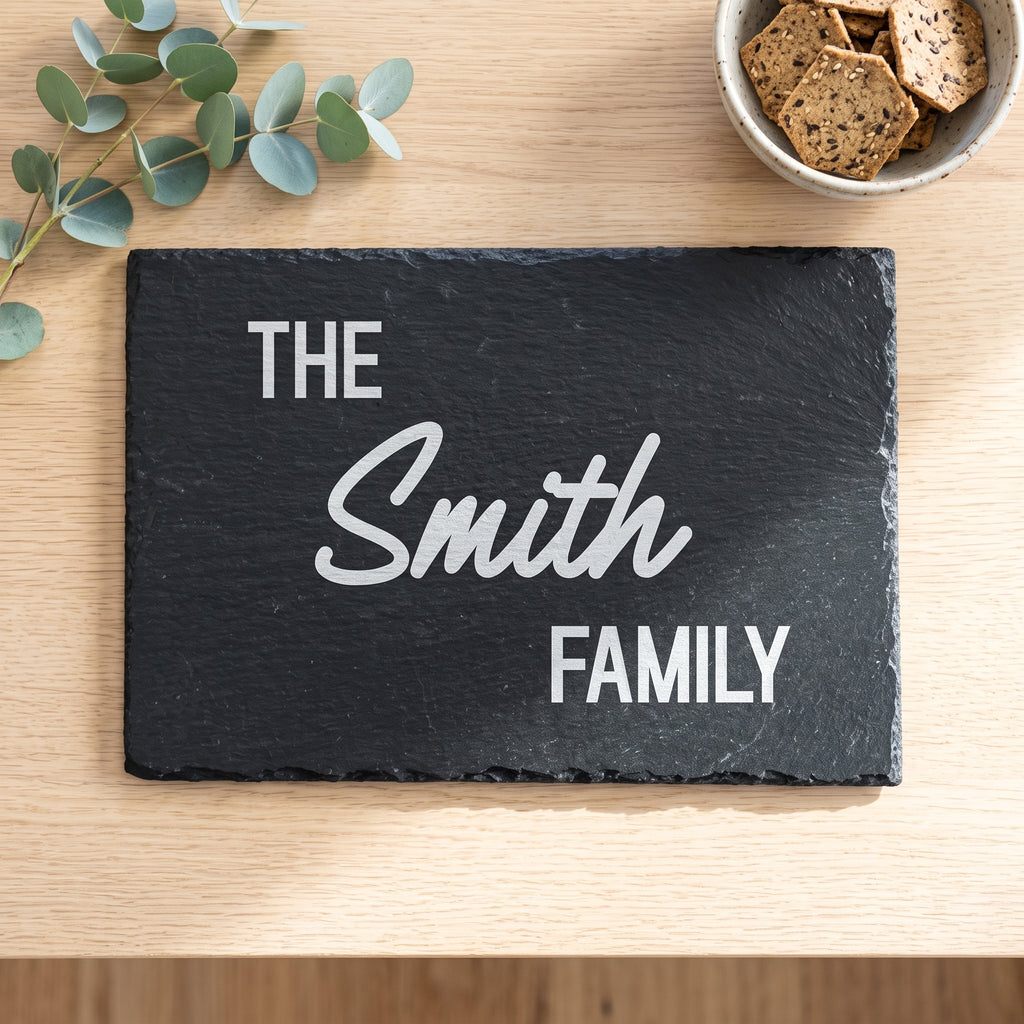 Close up of custom laser engraving on a 30cm x 20cm dark rectangular slate platter showing strong lettering and chipped edges.