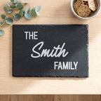 Close up of custom laser engraving on a 30cm x 20cm dark rectangular slate platter showing strong lettering and chipped edges.