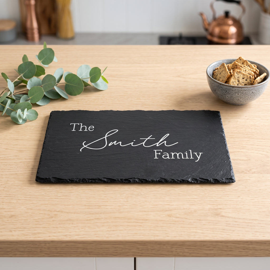 Close up of custom laser engraving on a 30cm x 20cm dark rectangular slate platter showing traditional lettering and chipped edges.