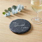 Close up of custom laser engraving on a dark round slate coaster featuring elegant traditional lettering.