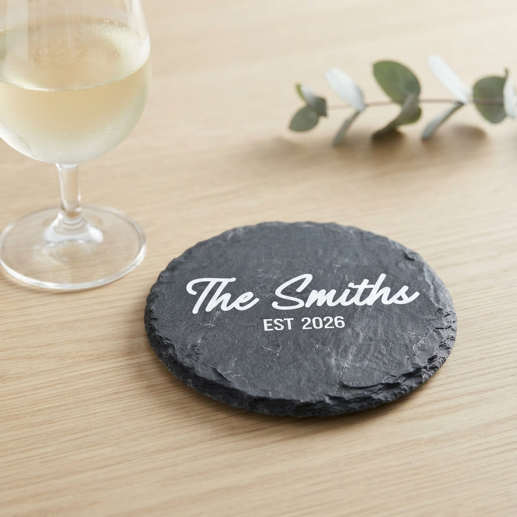 Close up of custom laser engraving on a dark round slate coaster featuring strong modern lettering.