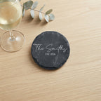 Close up of custom laser engraving on a dark round slate coaster featuring clean contemporary lettering.