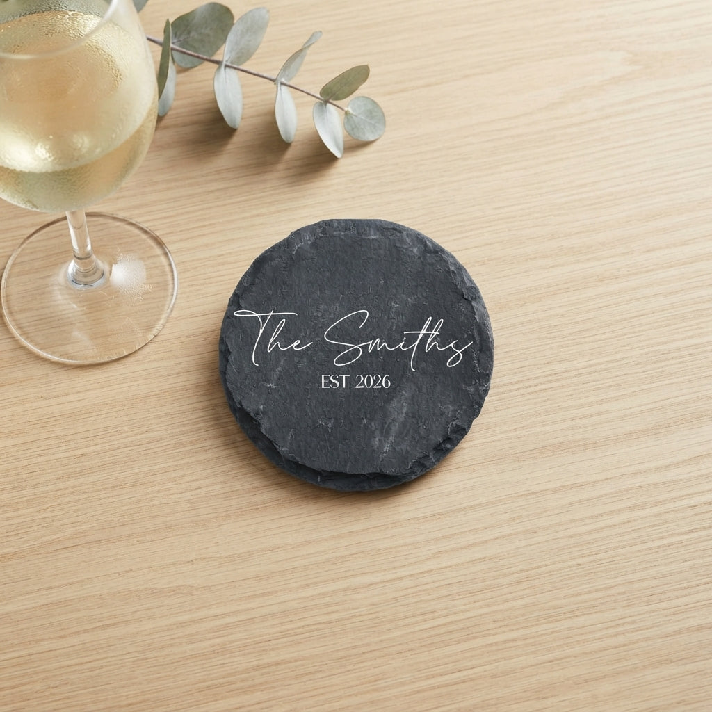 Close up of custom laser engraving on a dark round slate coaster featuring clean contemporary lettering.