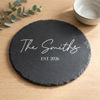 Close up of custom laser engraving on a 30cm dark round slate platter showing traditional script lettering and chipped edges.