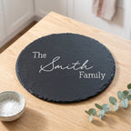 Close up of custom laser engraving on a dark round slate platter showing traditional balanced lettering and chipped edges.